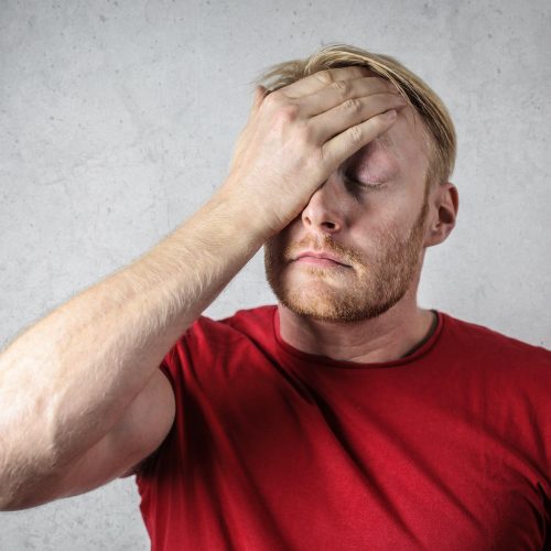 a-man-in-red-shirt-covering-his-face-3760043